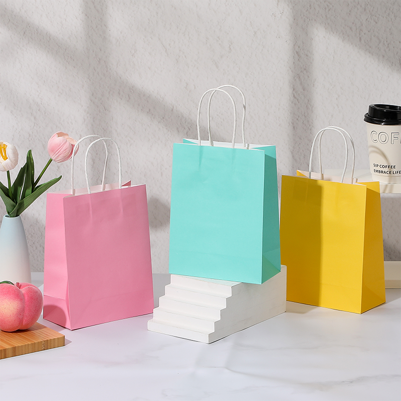 Bonbonfarbene Einkaufstaschen aus Kraftpapier mit gedrehten Papiergriffen